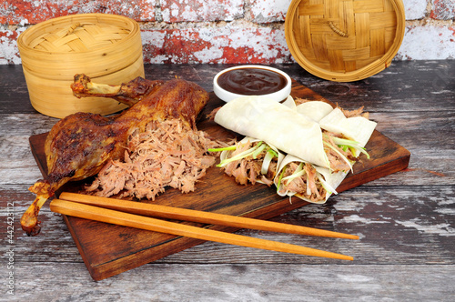 Aromatic half crispy duck with Chinese style pancakes, spring onions and hoisin sauce on a wooden board photo