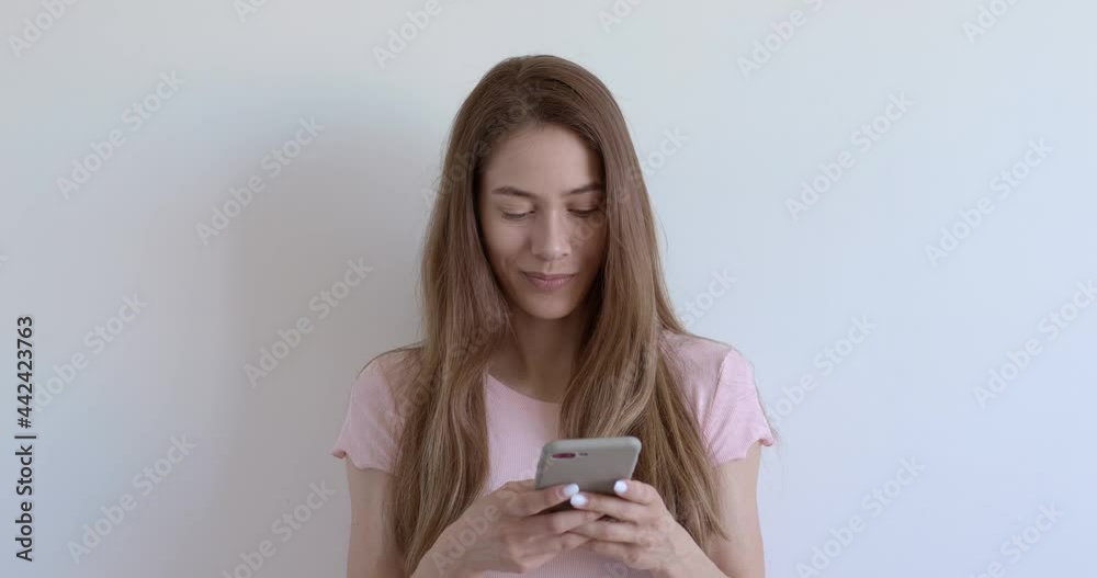 Adorable female chatting with someone on smartphone, typing message to boyfriend, flirting. Open-minded female is smiling, in casual wear. People lifestyle, copy space. Isolated white background Adorable female chatting with someone on smartphone, typing message to boyfriend, flirting. Open-minded female is smiling, in casual wear. People lifestyle, copy space. Isolated white background