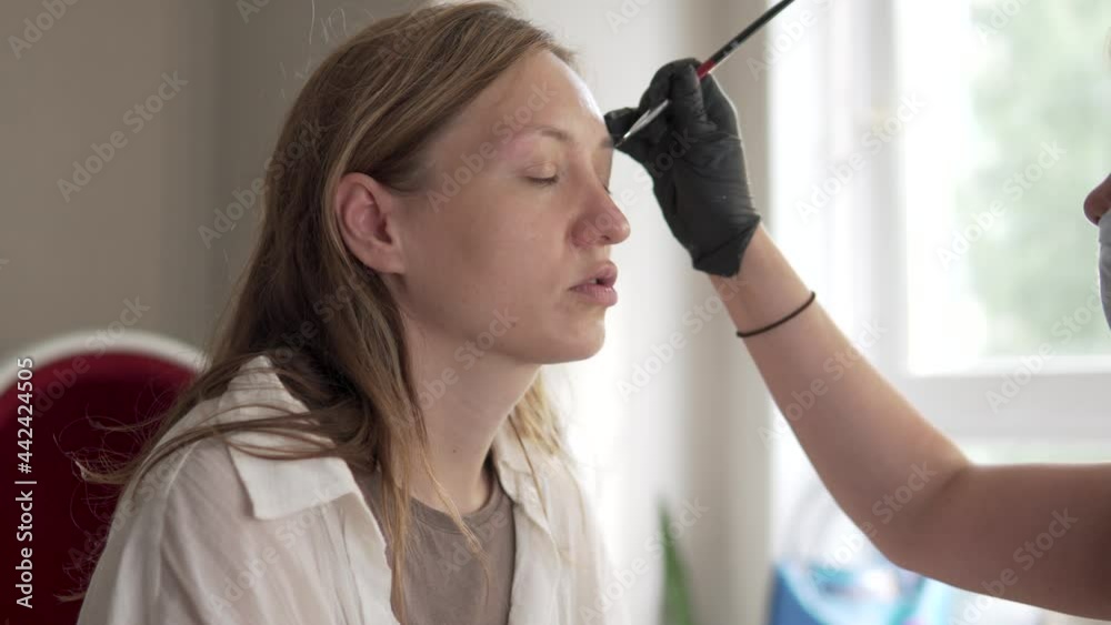 The master eyebrow paints the eyebrows of the customer with black paint. The master eyebrow paints the eyebrows of the customer with black paint.