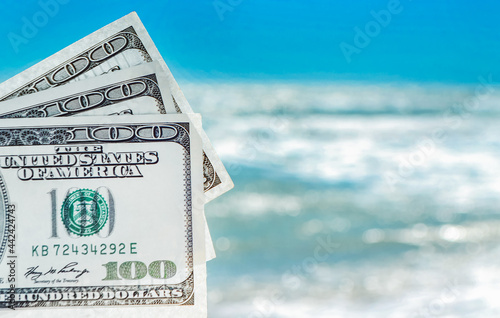 Girl holding money bill of 300 dollars on background of sea ocean photo