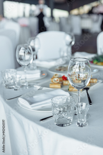 Table setting for a banquet or celebration. Empty wine glasses for spirits, champagne and juice. Set the table. Cloth napkins on a platter. Banqueting hall. Cold appetizers and salads.