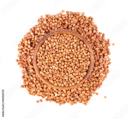 Roasted buckwheat grains in wooden bowl, isolated on white background. Dry brown buckwheat groats. Top view.