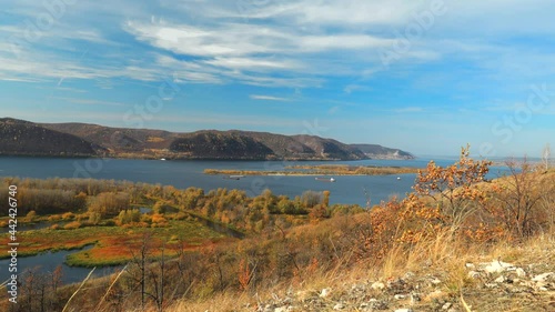 Wallpaper Mural Wide river flowing between high hills filmed in time lapse. The Volga river near the Zhigulevsky mountains. Autumn landscape. Orange colors of nature under the blue sky. Steamers move along the river. Torontodigital.ca
