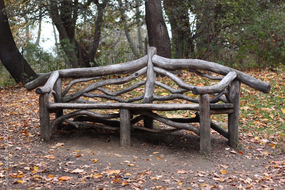 rustic wooden bench for people to sit in central park in manhattan autumn with trees in the background