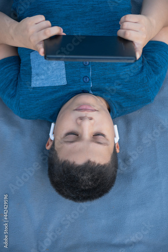 boy lying down listening to music with his tablet photo