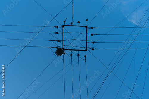 Electric wires and a street lamp against blue sky