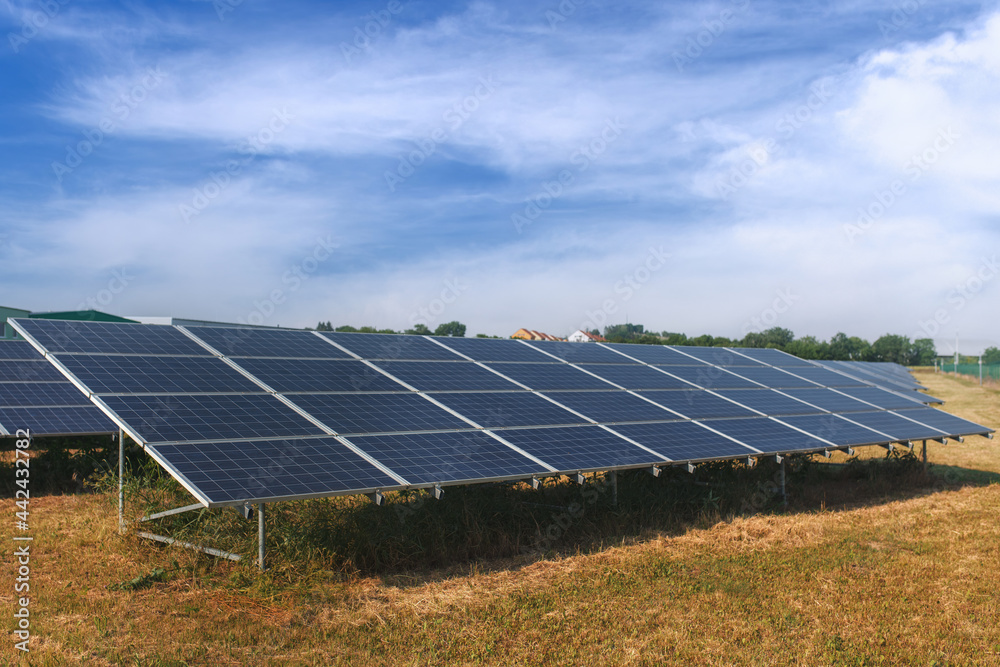 Solar panels in a field against a blue sky with clouds. Solar panels in a field against a blue sky with clouds.