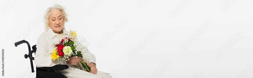 smiling elderly woman in wheelchair holding bouquet of flowers isolated on white, banner smiling elderly woman in wheelchair holding bouquet of flowers isolated on white, banner
