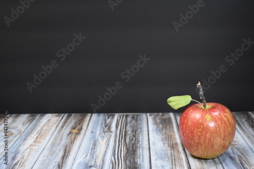 Red apple with a black background and wood table