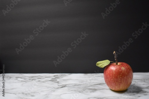 Red apple with a black background and marble table