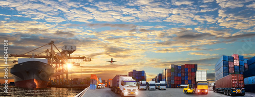 Container truck in ship port for business Logistics and transportation of Container Cargo ship and Cargo plane with working crane bridge in shipyard at sunrise, Business logistic import export concept © Travel mania