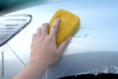 hand holding a sponge washing the car