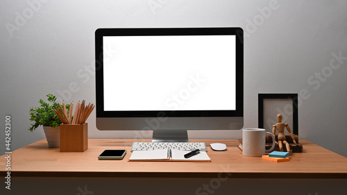 Modern workplace with computer, pencil holder and houseplant on wooden table.