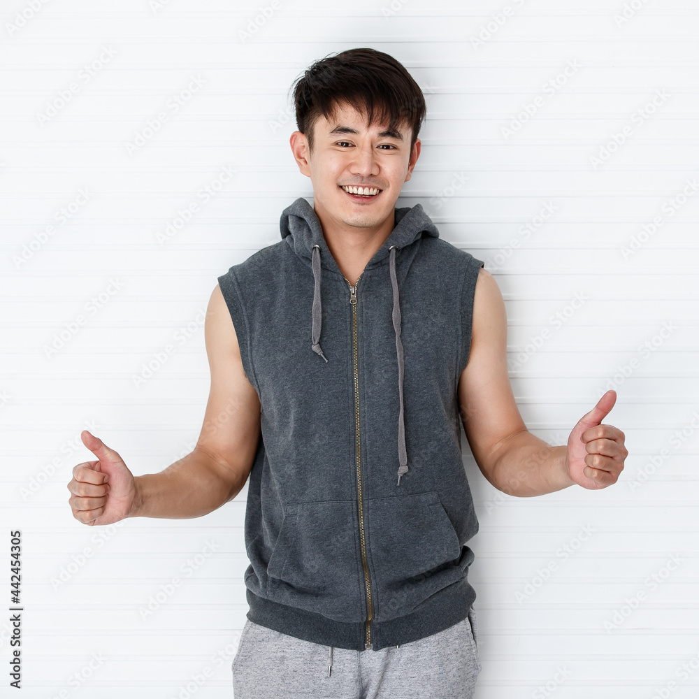 Asian handsome fit smiling man holding hand thumbs up show great wearing sleeveless t-shirt gray sportswear in white background. Asian handsome fit smiling man holding hand thumbs up show great wearing sleeveless t-shirt gray sportswear in white background.