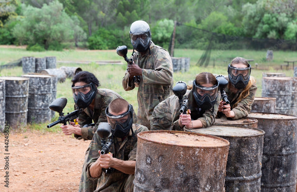 Group of people in full gear playing paintball on shooting range