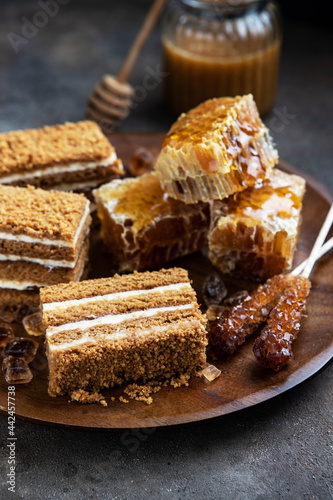 Honey cake slices and honeycomb on dark background