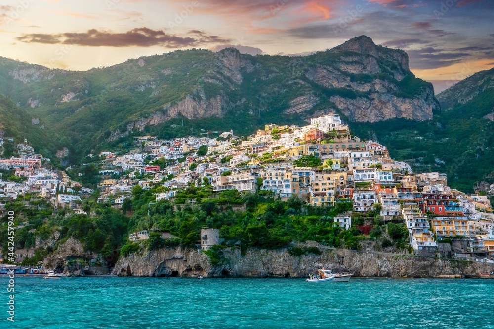 Viewed from the sea, a wide angle shot of Positano, a former fishing village now a chic seaside resort with pastel colored villas and hotels perched on the steep cliffs of the Amalfi Coast in Italy.