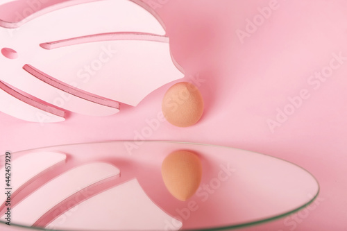 Makeup sponge and mirror on color background