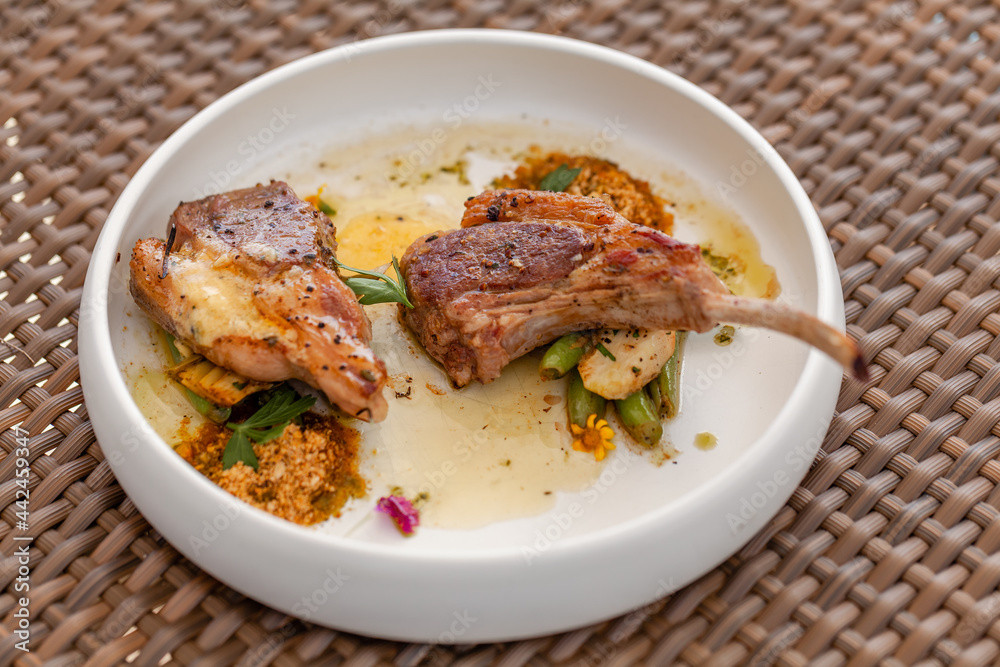 Fresh Grilled Lamb Steak on White Plate in Outdoor Restaurant in Summer Day. Fine Dining Food - Roasted Lamb Meat with Butter and Vegetables on Table