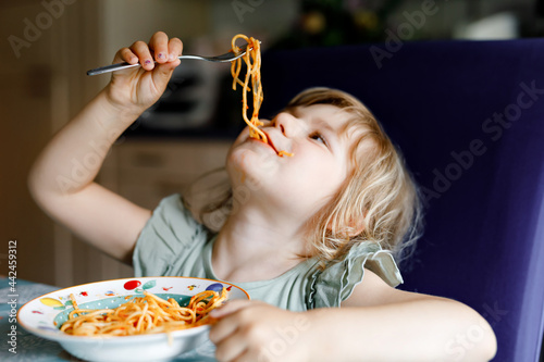 Obraz na płótnie Adorable toddler girl eat pasta spaghetti with tomato bolognese with minced meat. Happy preschool child eating fresh cooked healthy meal with noodles and vegetables at home, indoors. w salonie