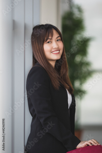 Confident businesswoman standing in office corridor and looking at camera © Bangkok Click Studio