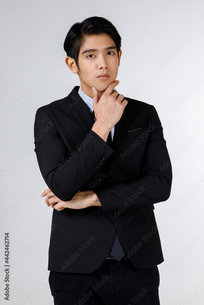 Portrait shot of Asian young handsome happy intelligence successful businessman in black formal suit stand hold hand touch chin brooding thinking alone in front of white wall background Portrait shot of Asian young handsome happy intelligence successful businessman in black formal suit stand hold hand touch chin brooding thinking alone in front of white wall background