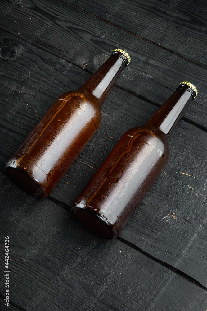 Beer bottle, on black wooden background, with copy space for text
