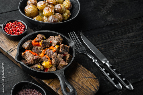 Goulash, beef stew, in cast iron frying pan, on black wooden background