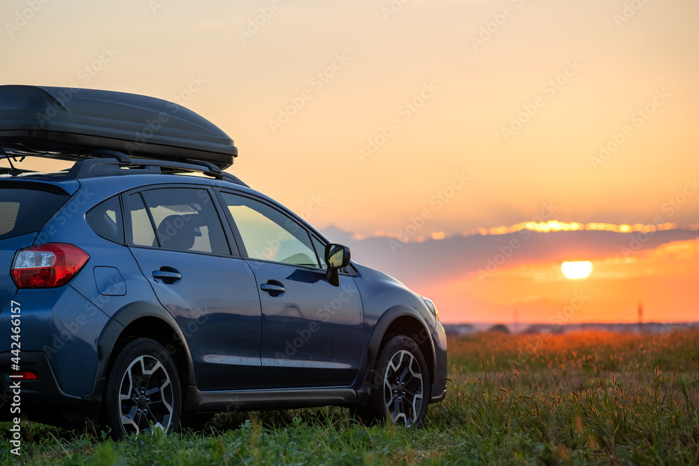 SUV car with roof rack luggage container for off road travelling parked at roadside at sunset. Road trip and getaway concept. - obrazy, fototapety, plakaty 