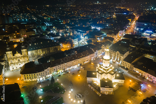Aerial view of bright illuminated streets and buildings in Ukrainian Ivano-Frankivsk city center at night.