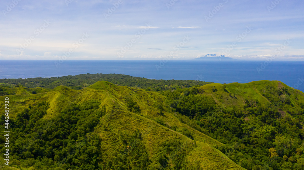 Aerial view of mountains and hills with rainforest and green grass under a blue sky with clouds on a Sunny summer day. Bohol, Philippines. Aerial view of mountains and hills with rainforest and green grass under a blue sky with clouds on a Sunny summer day. Bohol, Philippines.