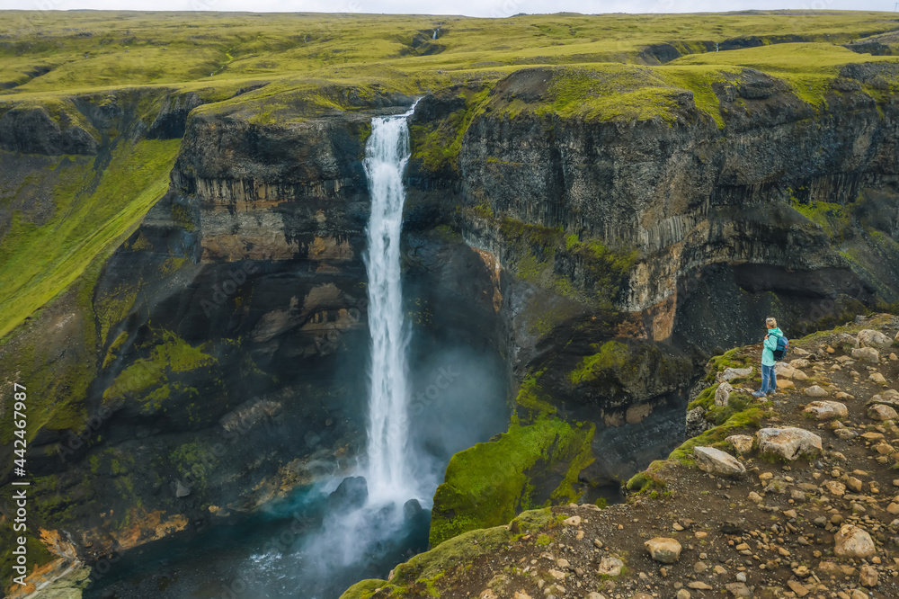 Aerial view of woman with backpack enjoying Haifoss waterfall of Iceland Highlands