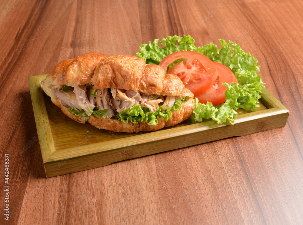 fried chicken or tuna fish with sesame sauce in baked crispy croissant bread and vegetables salad on wood table fresh halal pastry sandwich menu fried chicken or tuna fish with sesame sauce in baked crispy croissant bread and vegetables salad on wood table fresh halal pastry sandwich menu