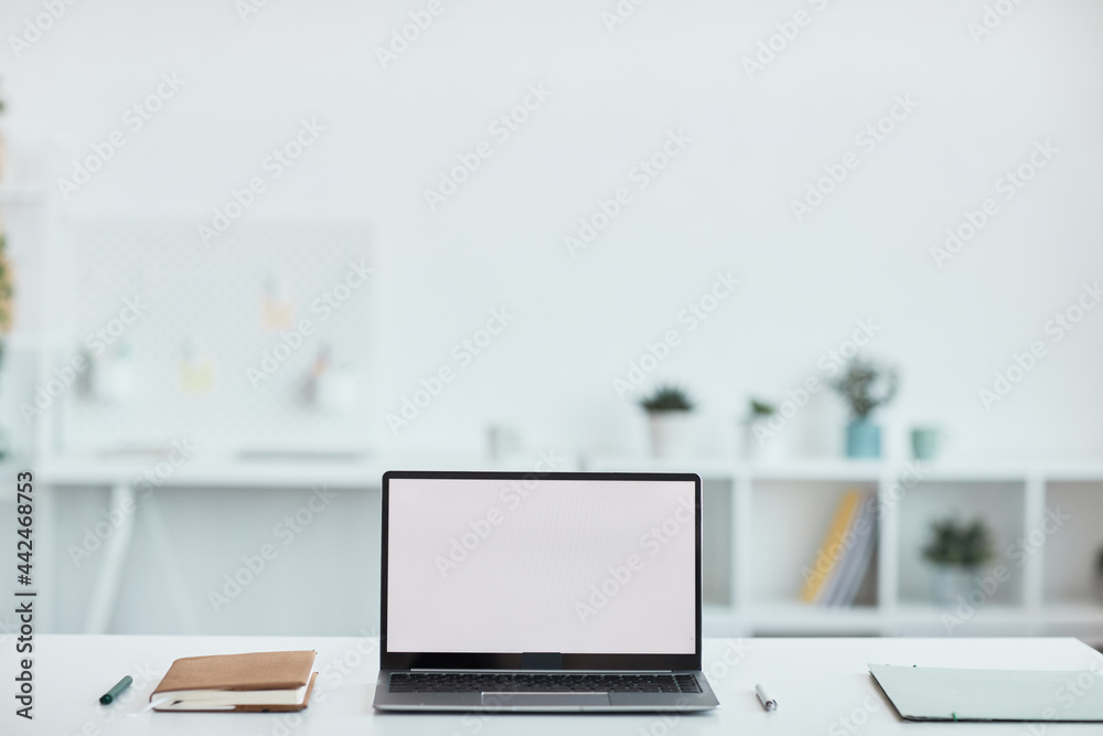 Minimal background image of open laptop with blank white screen at workplace in office, copy space - obrazy, fototapety, plakaty 