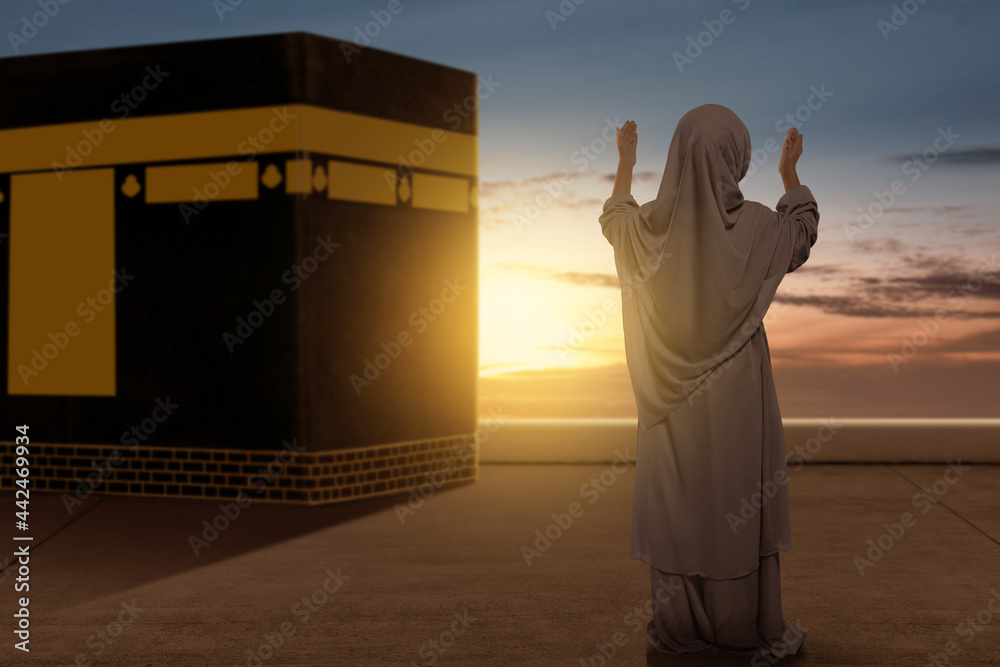 Rear view of Asian Muslim little girl in a veil standing and raised ...