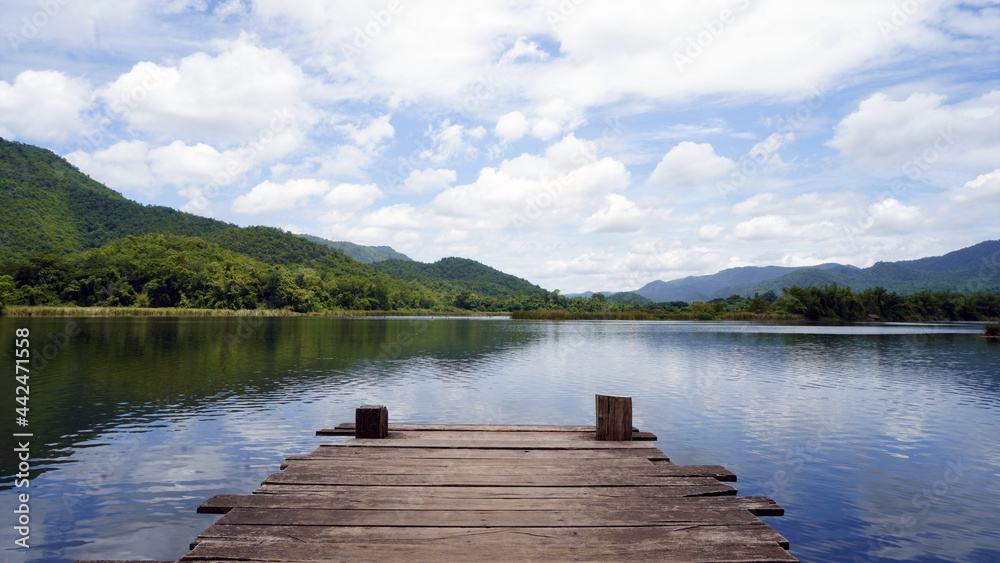 Wooden pier on lake in the mountain. Panoramic view of Wooden bridge lake with Green mountain, bright blue sky and lake at the background with Empty wooden floor. 
