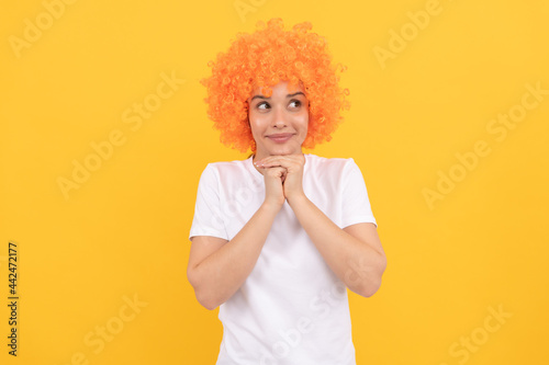 dreamy freaky woman in curly clown wig for party, dreaming
