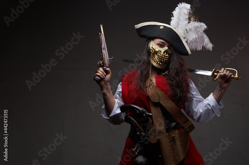 Tattooed female pirate posing with cutlass and gun photo