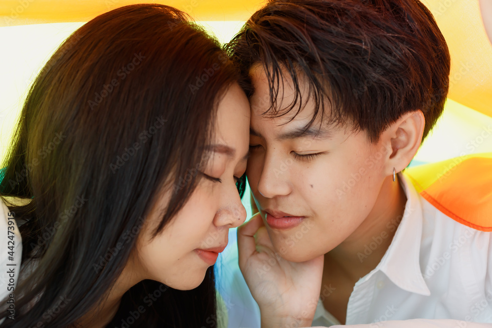 LGBTQ couple lovers, a handsome girl as a man or butch femme covered .with the rainbow flag the symbol of LGBT, spending and sharing loving time with fun, warmth, and happiness LGBTQ couple lovers, a handsome girl as a man or butch femme covered .with the rainbow flag the symbol of LGBT, spending and sharing loving time with fun, warmth, and happiness