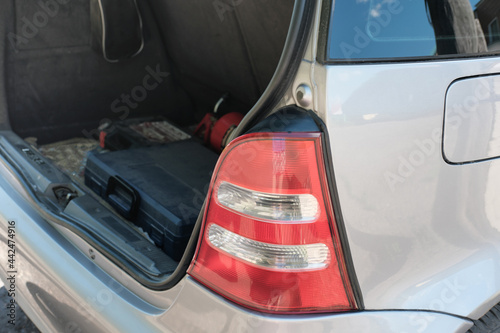 taillight of a silver hatchback car and open trunk with repair tool box. summer travel and car jorney concept