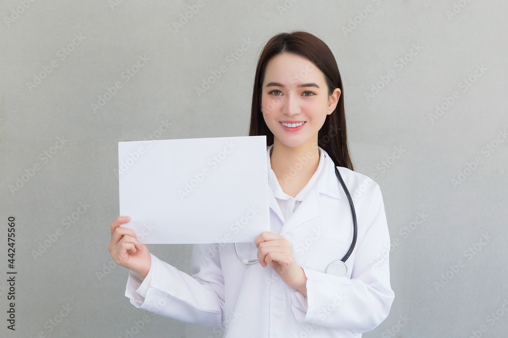 Asian woman doctor who wears medical coat holds and shows white paper to present something in healthcare concept. Asian woman doctor who wears medical coat holds and shows white paper to present something in healthcare concept.