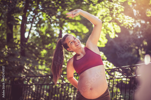 Pregnant woman working exercise outside. © liderina