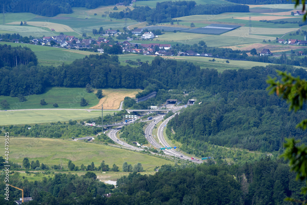 Rural landscape seen from local mountain Uetliberg on a summer day with highway and portal to Uetliberg tunnel. Photo taken June 29th, 2021, Zurich, Switzerland.