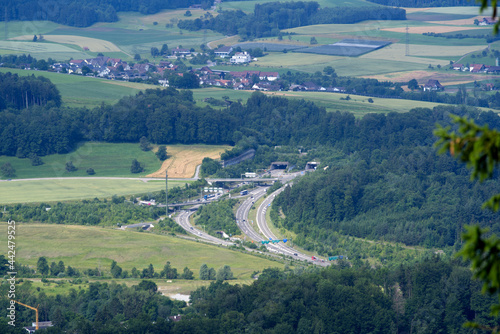Rural landscape seen from local mountain Uetliberg on a summer day with highway and portal to Uetliberg tunnel. Photo taken June 29th  2021  Zurich  Switzerland.