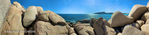 granite rocks sculpted by wind and water, flowers and lichen in front of sky and light reflections in the water surface on the north coast of 