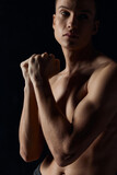 sporty guy with pumped up arm muscles on a black background looking to the side close-up 