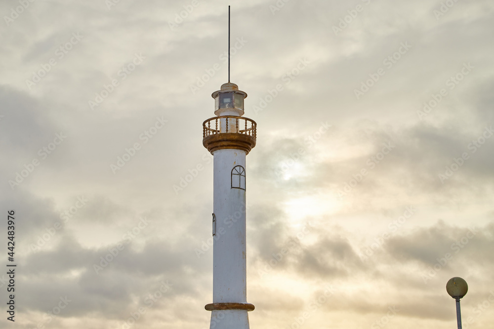 A small lighthouse in evening with sunset and a sky with clouds