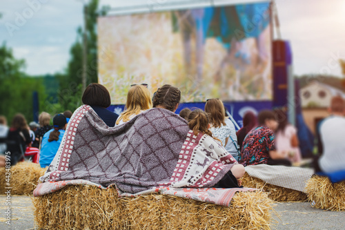 Canvas Print Three girls watching a movie in the open air, wrapped in a blanket
