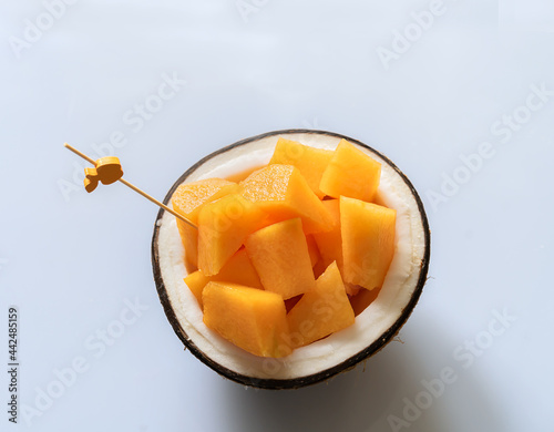 Melon slices on the half of natural cocco nut on the white background photo