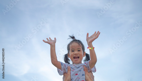 Happy funny asian cute girl flying in fathers arms on sky background.selective focus 